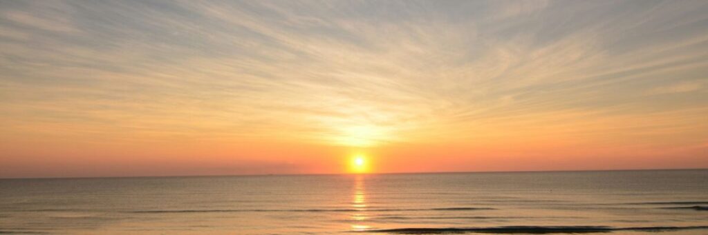 海平線に沈む大きな夕日の温かな光。HSPが素のままの自分でいられ、疲れた時に安心して戻ってこられる居場所「Tealsホーム」の安らぎを象徴しています