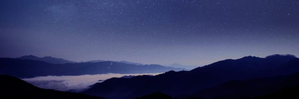 薄明かりの雲海とシルエットの山並み、その上に広がる満天の星空。周囲の膨大な情報をバックグラウンドで処理し続け、常に脳が動き回っている状態を表現するイメージ。